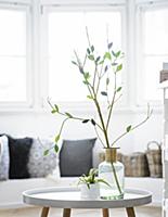 Green paper leaves on branch in vase