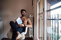 Mid adult man with tattooed chest sitting on chair