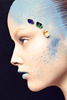 A young woman dusted with blue powder with three g