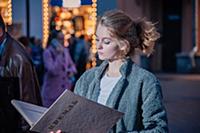 Девушка в сером пальто с книгой в руках на улице г