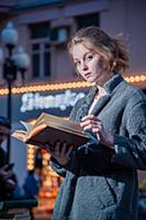 Девушка в сером пальто с книгой в руках на улице г